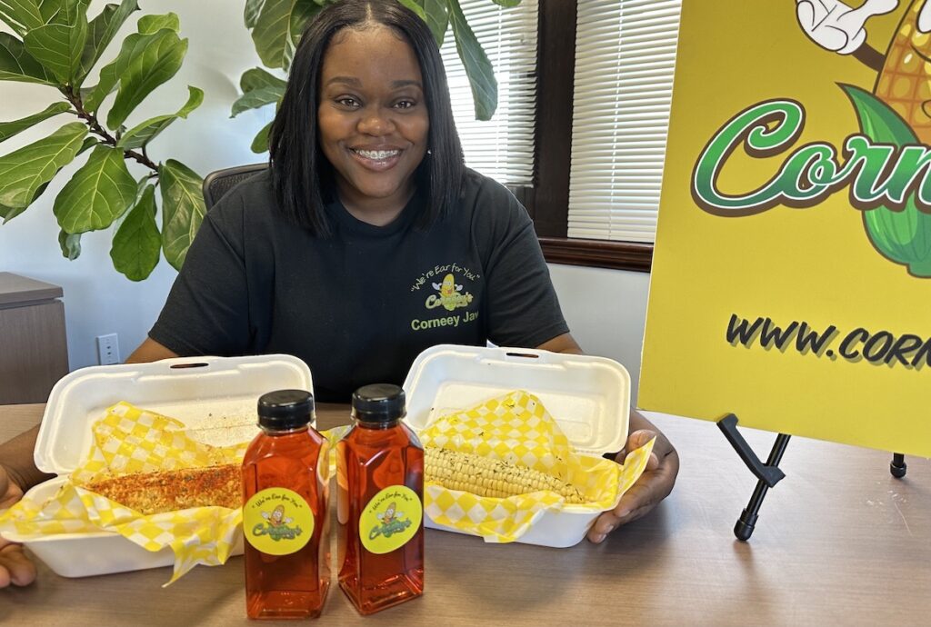 NijaWigginsCorneys 2 Nija Wiggins poses, smiling, with some of her corn on the cob specialties in front of her.