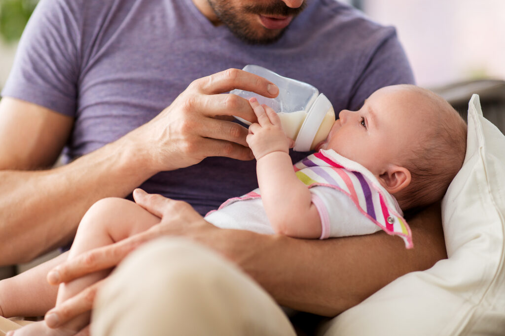 family, parenthood and people concept – close up of father feedi Father feeding his baby daughter