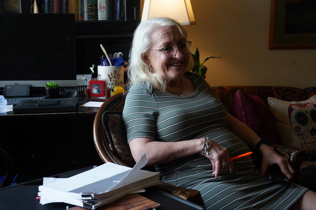 Rhonda Isser sits in a chair in her home.