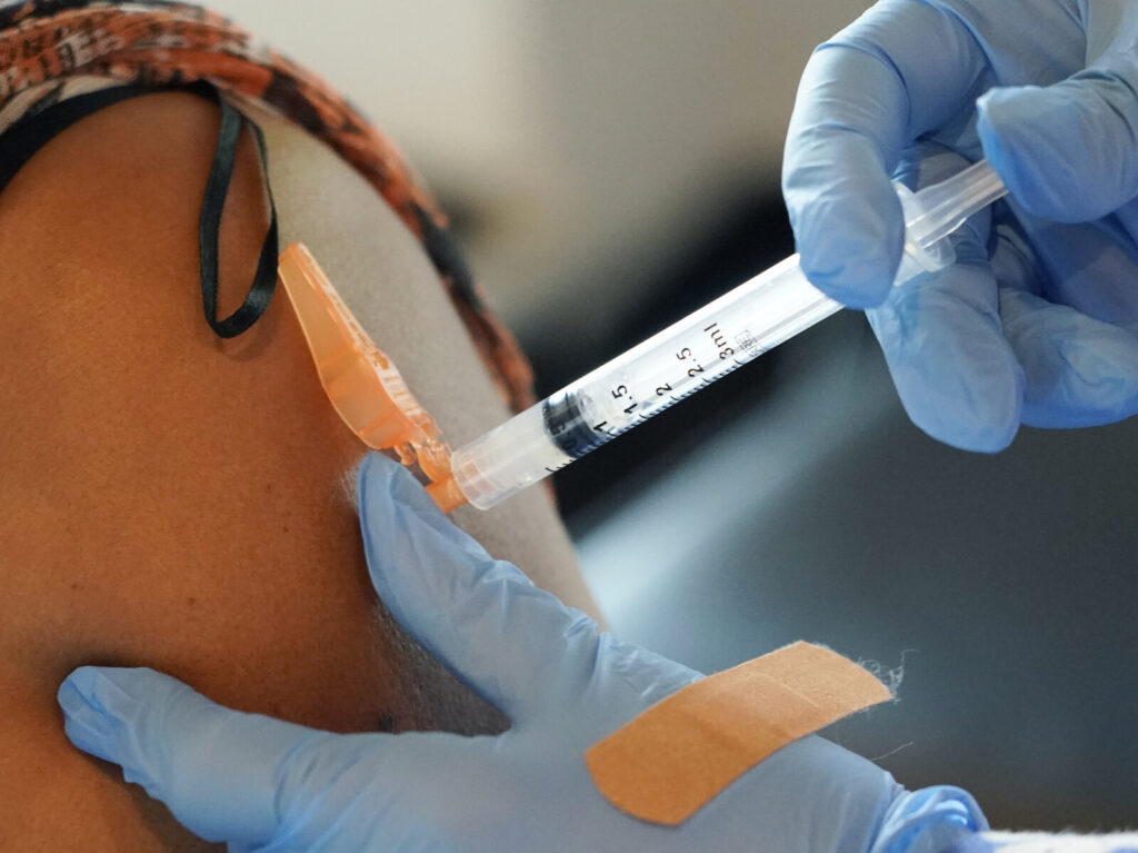 Maggie Bass A person gives someone a COVID-19 vaccine