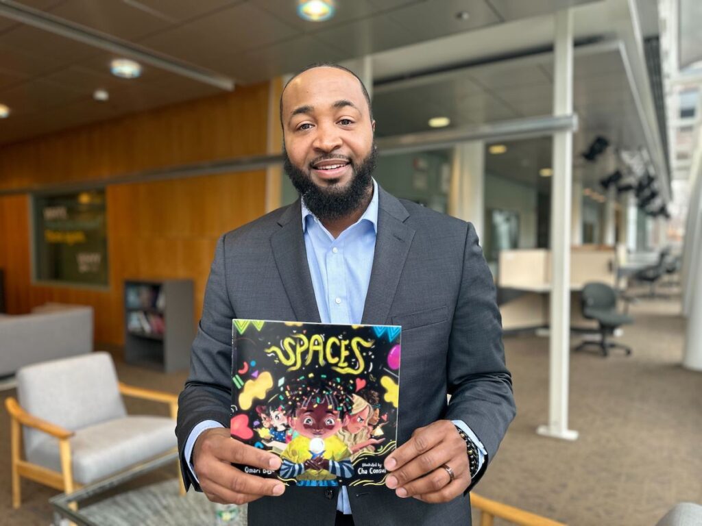 omari-baye Omari Baye holds a book he authored called “Spaces”