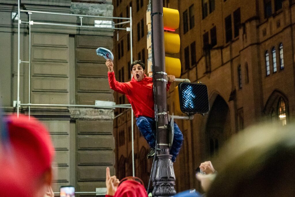 phillies-celebration-broadstreet-nlcs11-b-scaled A fan celebrating the Phillies pennant win atop a street light on Broad. (Nathan Morris / Billy Penn)