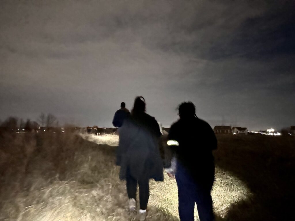 Volunteers walk down a path outside at night
