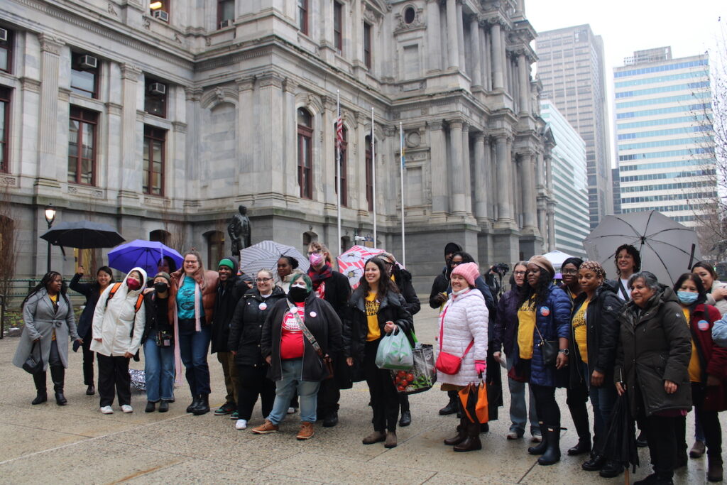 A group of people stands outside of City Hall