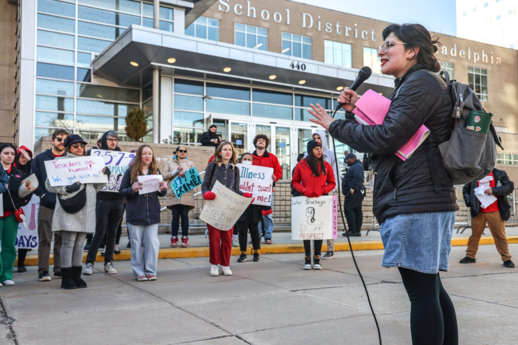 02 29 2024 reduced size PFT sick policy protest-4 Jessie Shapiro speaks into a microphone in front of protesters at the School District of Philadelphia