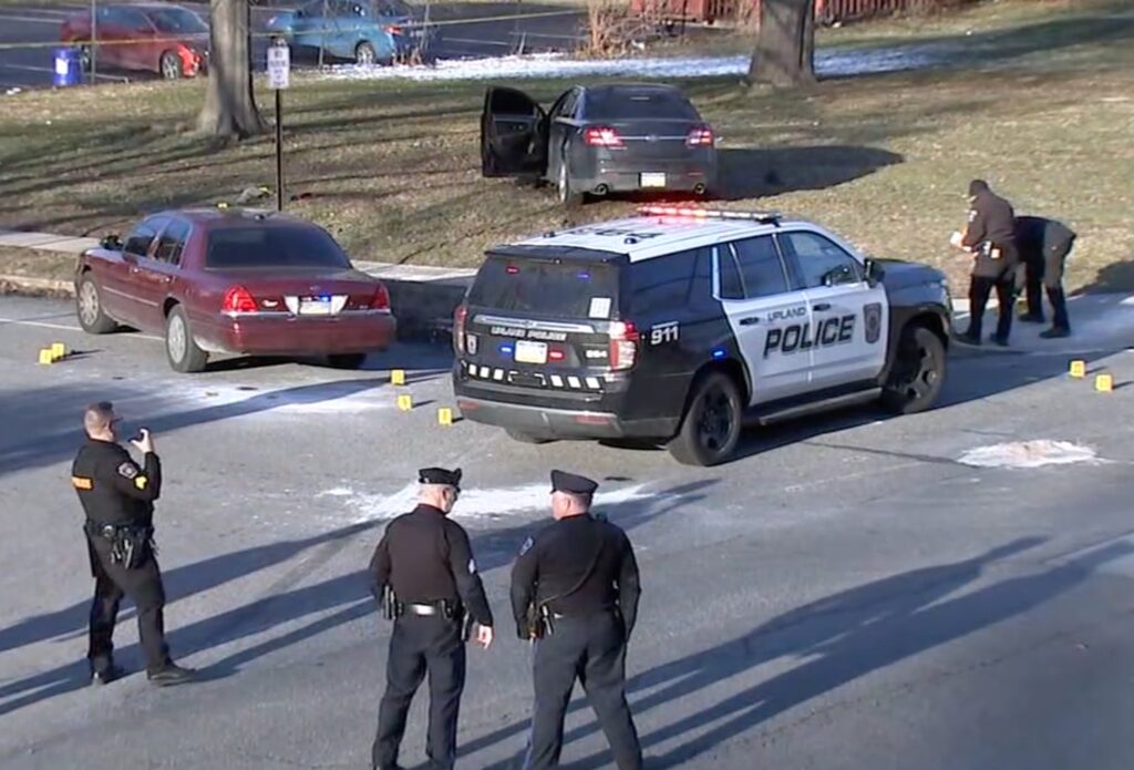delco-officer-shot Officers stand around a police car at the scene of a shooting.