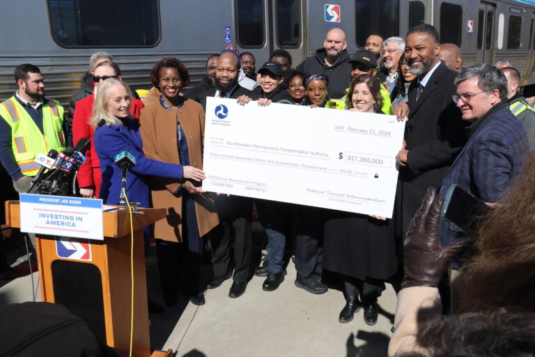 Federal, local, and transit officials celebrated, holding a check representing a $317 million grant