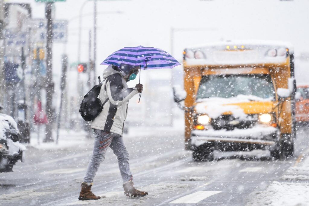 A person crosses a street during a winter snow storm in Philadelphia, Tuesday, Feb. 13, 2024.