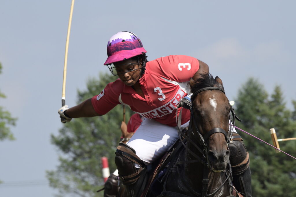 Shariah Harris rides a horse while playing polo