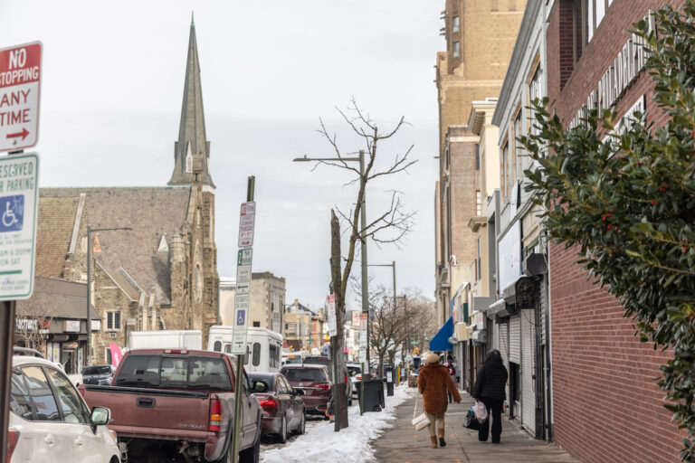 People walk down the sidewalk at Chelten Ave. and Greene St. in Germantown