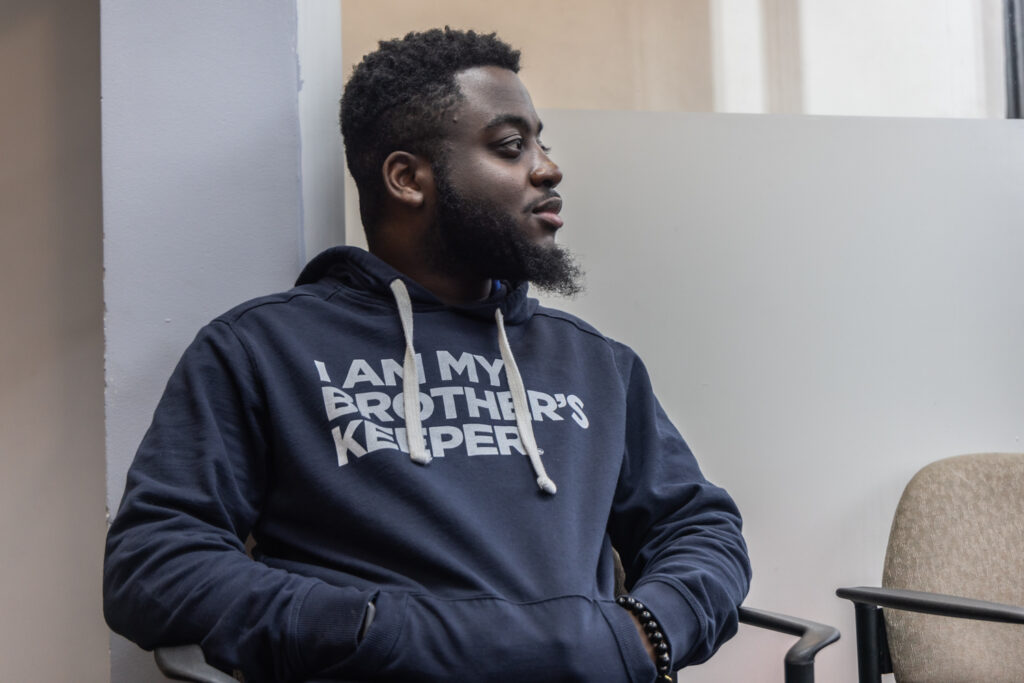 Andrew Ankamah Jr. looks to his left while sitting in a chair in a room.