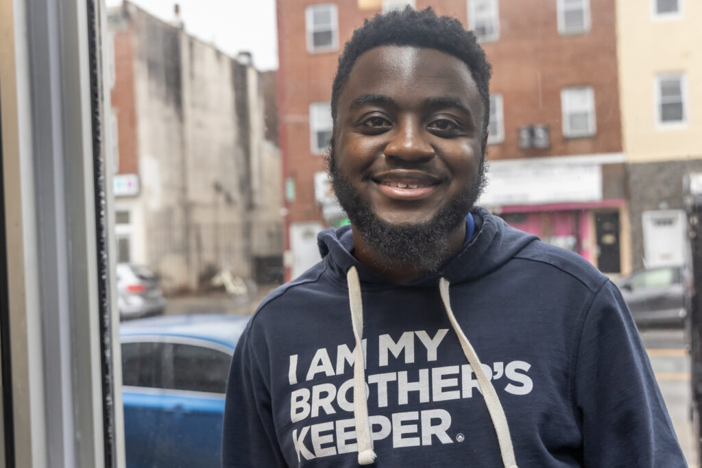 Andrew Ankamah Jr. smiles while posing for a photo in front of a window.