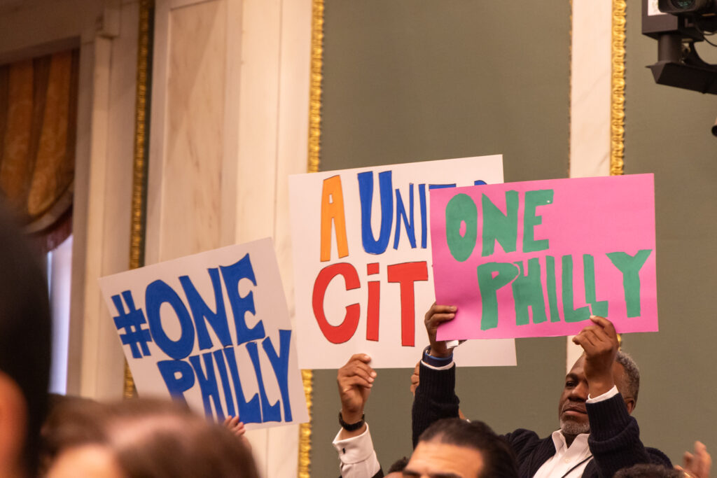 People holding up signs during Mayor Parker's speech