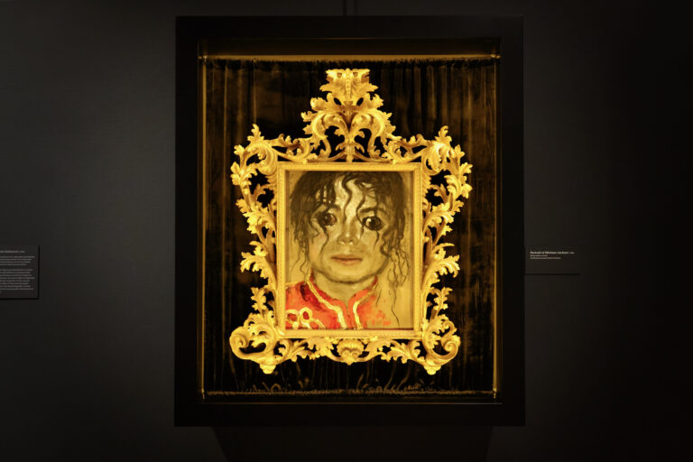 Jamie Wyeth's portrait of pop icon Michael Jackson floats in the darkness surrounding it's painted gold frame. (Emma Lee/WHYY)