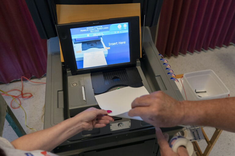 File photo: A polling judge (right) helps guide a voter's ballot into a voting machine during the Pennsylvania primary election, at Mont Alto United Methodist Church in Alto, Pa., on May 17, 2022.