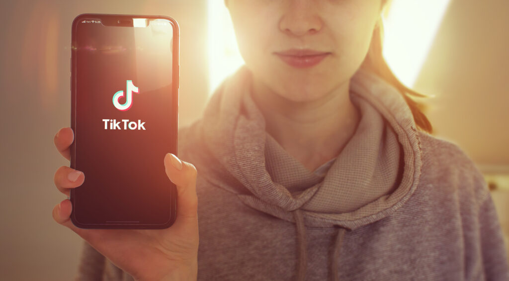 KYIV, UKRAINE-JANUARY, 2020: Tiktok on Smartphone Screen. Young Girl Showing Smartphone Screen with Tiktok on it while Looking at the Camera. Focus on Smartphone.