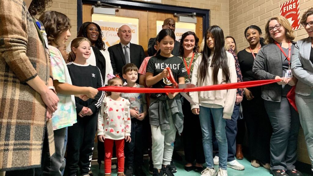 Students and staff members cut a ribbon at a new school-based health center