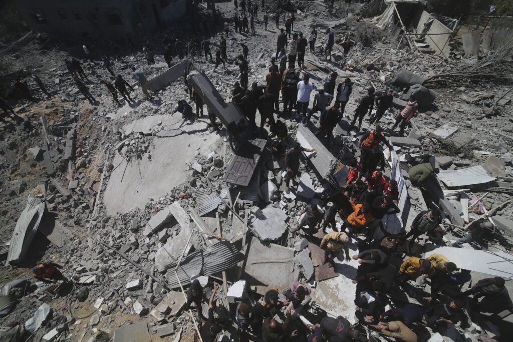 Palestinians look at a residential building destroyed in an Israeli strike in Rafah, Gaza Strip, Tuesday, March 20, 2024.