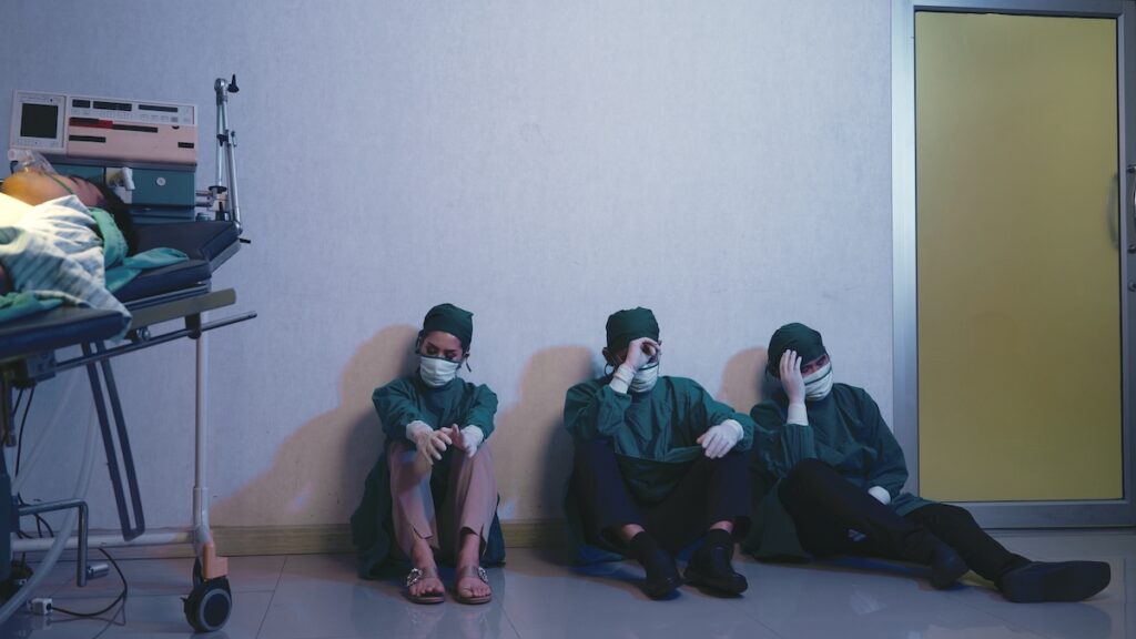 Tired Doctor, Group Of Surgery Doctors Sadness Fatigue After Surgery, Emotional Sitting Stress Of Ov Surgical team tired and overworked after operation. (Bigstock/Sorapop)