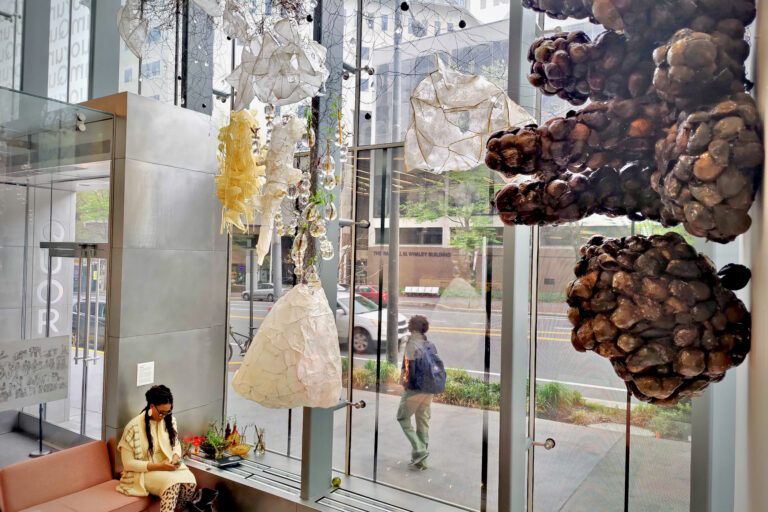 Artist Jasmine Murrell sits underneath her installation