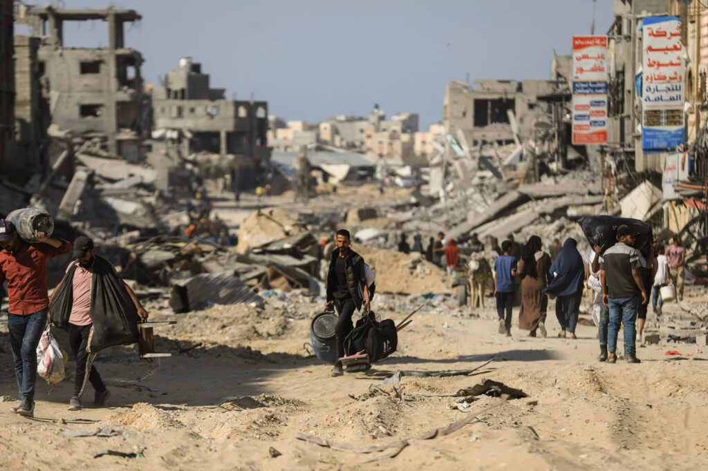 Khan-Younis-2024 People walk past destroyed buildings along a road in Khan Younis on April 7, 2024