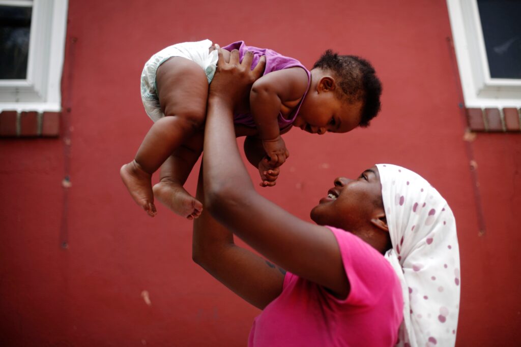 A mother holds her daughter in the air.