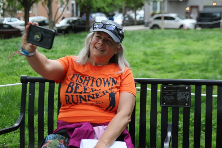 A person takes a selfie on a bench in Palmer Park