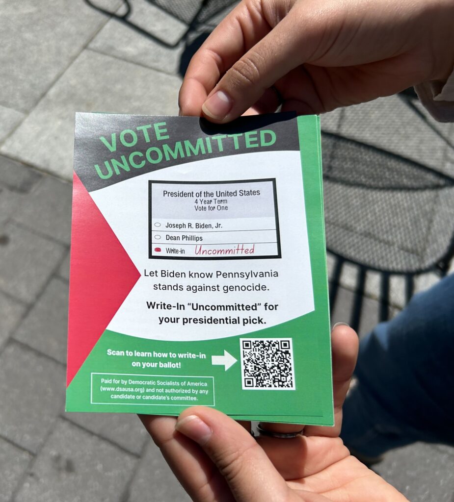 An organizer holds a flyer explaining how to vote "uncommitted."