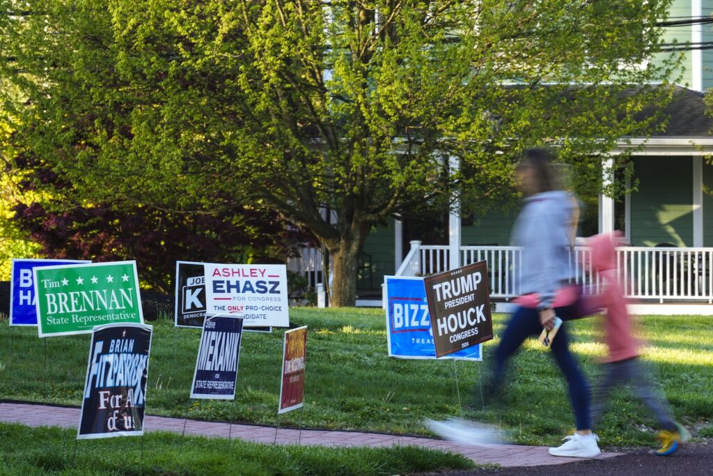Election 2024 Pennsylvania A voter and child walk past campaign signs posted outside of a polling site in Doylestown, Pa.