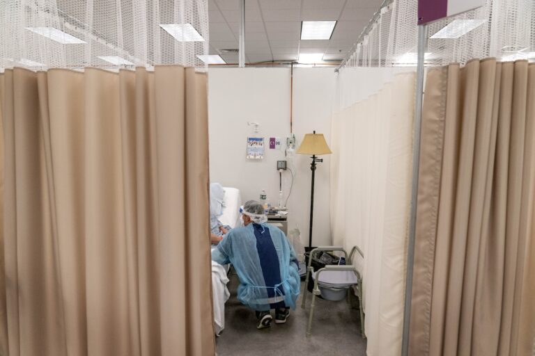 A physical therapist works with a patient at a field hospital.