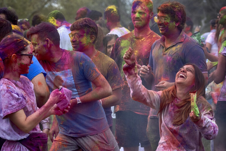 People dancing and throwing colored powder on each other
