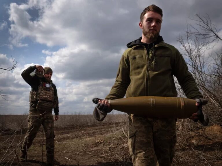 Ukrainian soldiers carry shells to fire