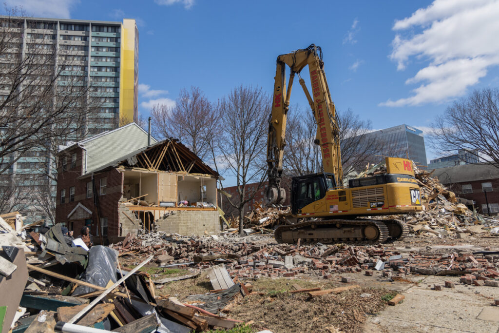 an excavator with the demolished UC Townhomes Demolition of the housing project