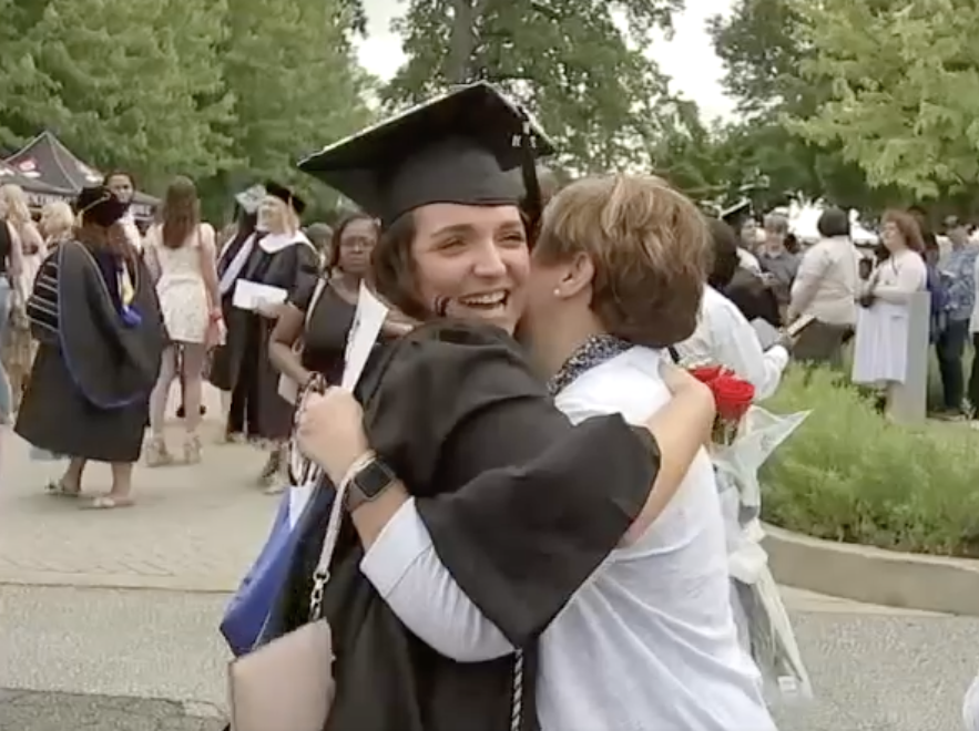 cabrini-final-graduation a graduate hugs a woman at graduation