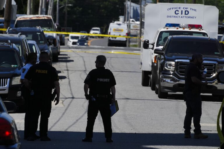 Law enforcement stand at the scene of a fatal shooting at Delaware County Linen, Wednesday, May 22, 2024, in Chester, Pa.