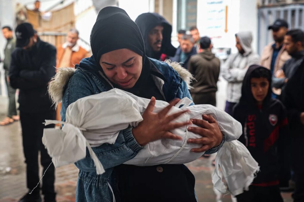 gaza-women-children A woman mourns as she carries the shrouded body of a child killed following overnight Israeli strikes on Rafah in the southern Gaza Strip, on May 6. (AFP via Getty Images)