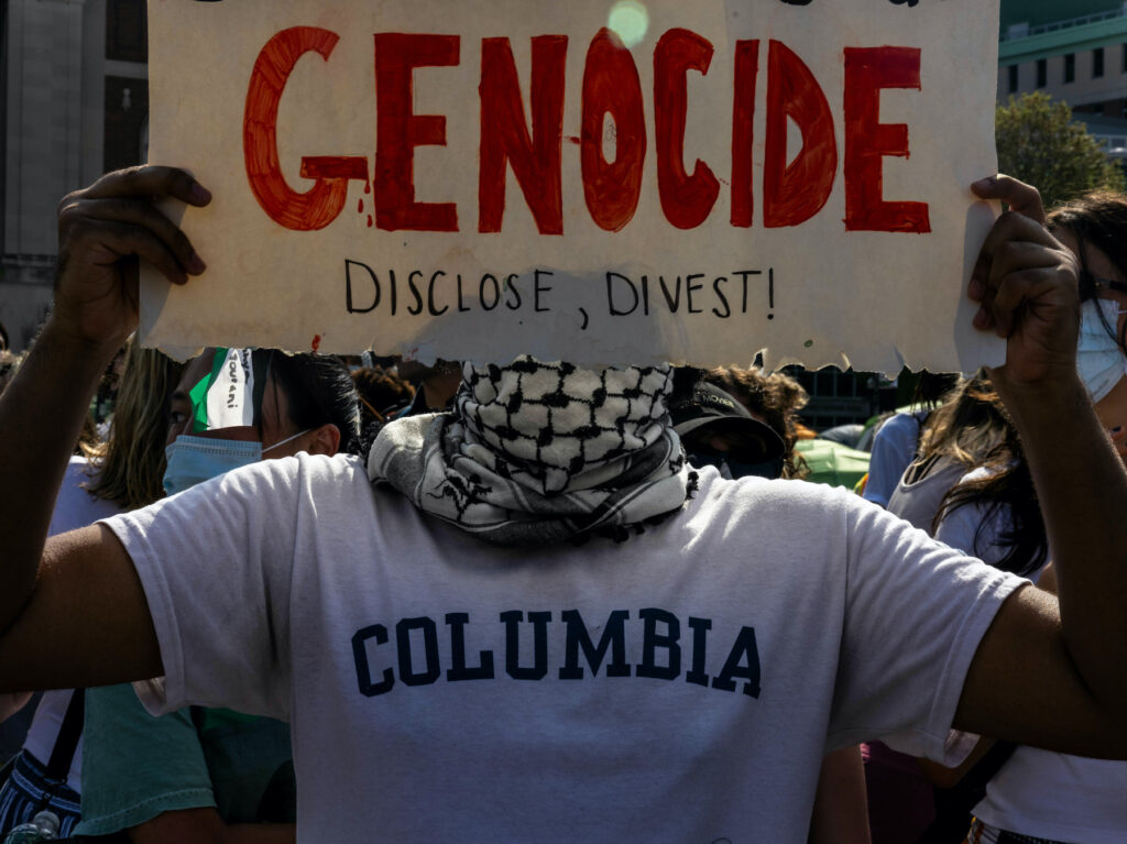 Columbia University Issues Deadline For Gaza Encampment To Vacate Campus Protester holds a sign that says 'Genocide'