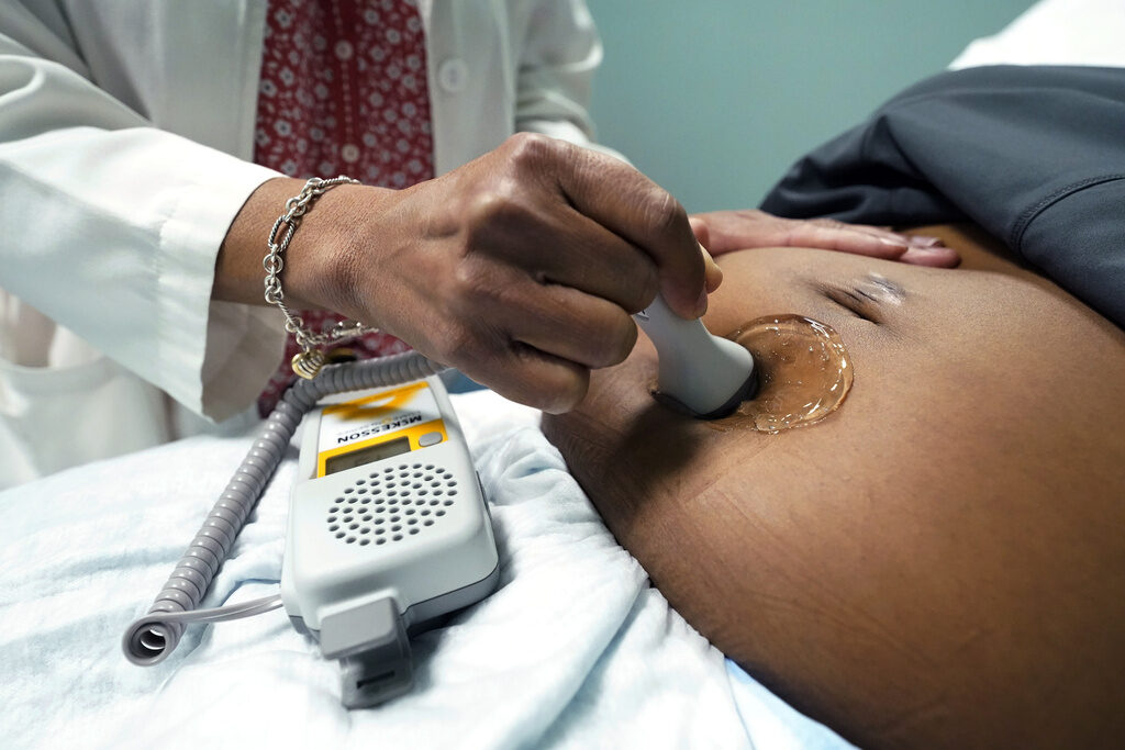 Maternal Morbidity A doctor uses a hand-held Doppler probe on a pregnant woman