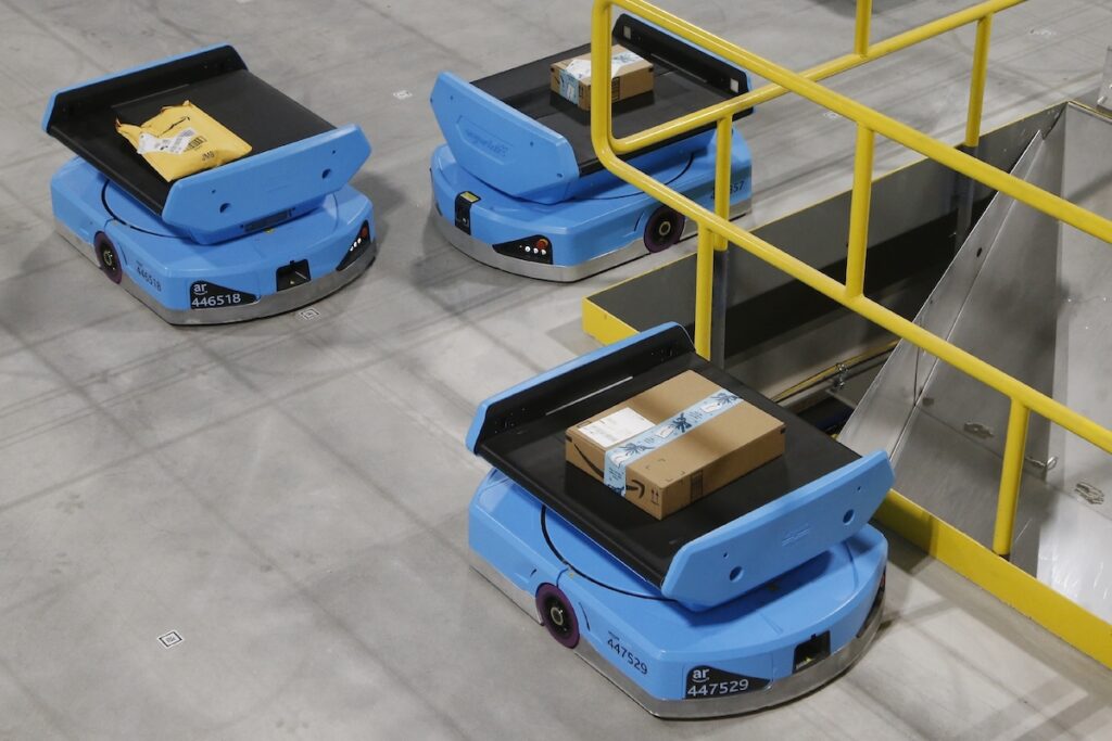 In this Dec. 17, 2019, file photo Amazon robots move along the warehouse floor with packages before finding the proper delivery chute at an Amazon warehouse facility in Goodyear, Ariz. (AP Photo/Ross D. Franklin, File)
