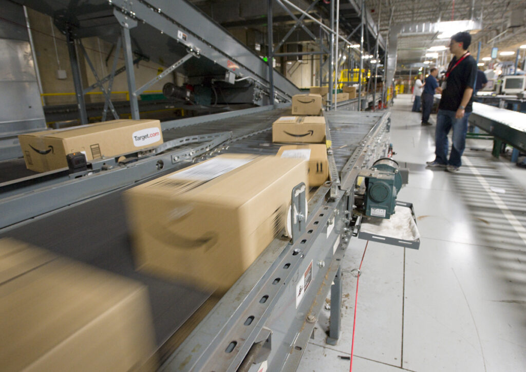 An Amazon.com employee watches boxes speed by on a conveyor belt at one of their warehouses. (AP file Photo/Scott Sady)