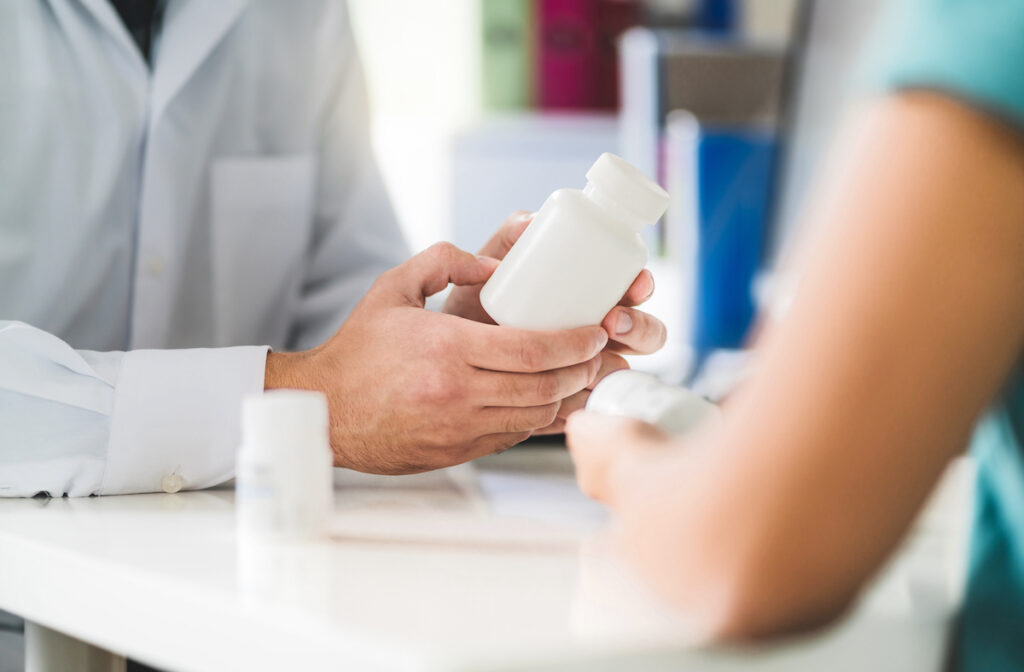 Doctor Consulting Patient About Right Medication. Physician Holding Medicine And Pills In Hand. Phar Doctor consulting patient about right medication.