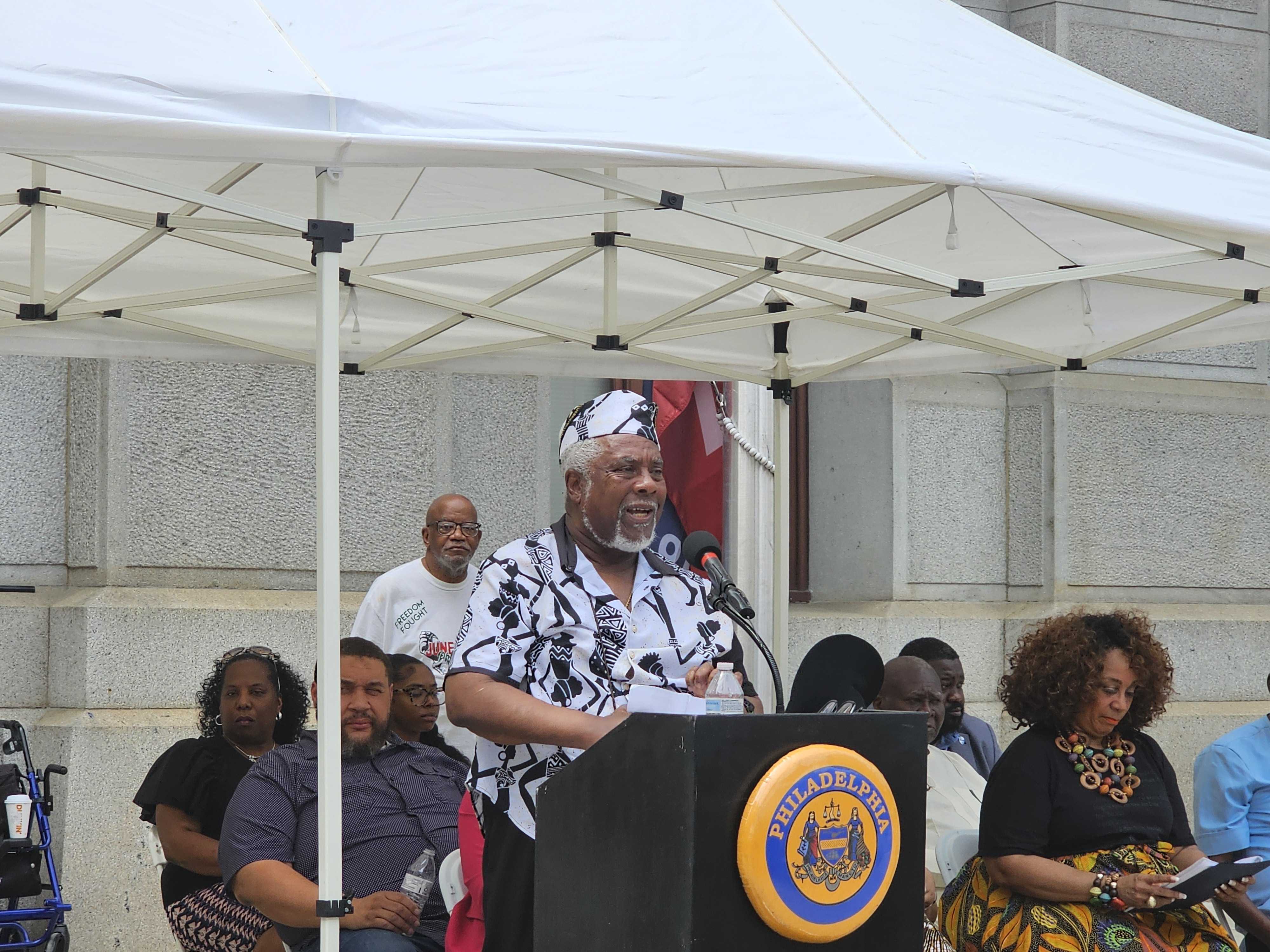 Kofi Assante speaks at a podium