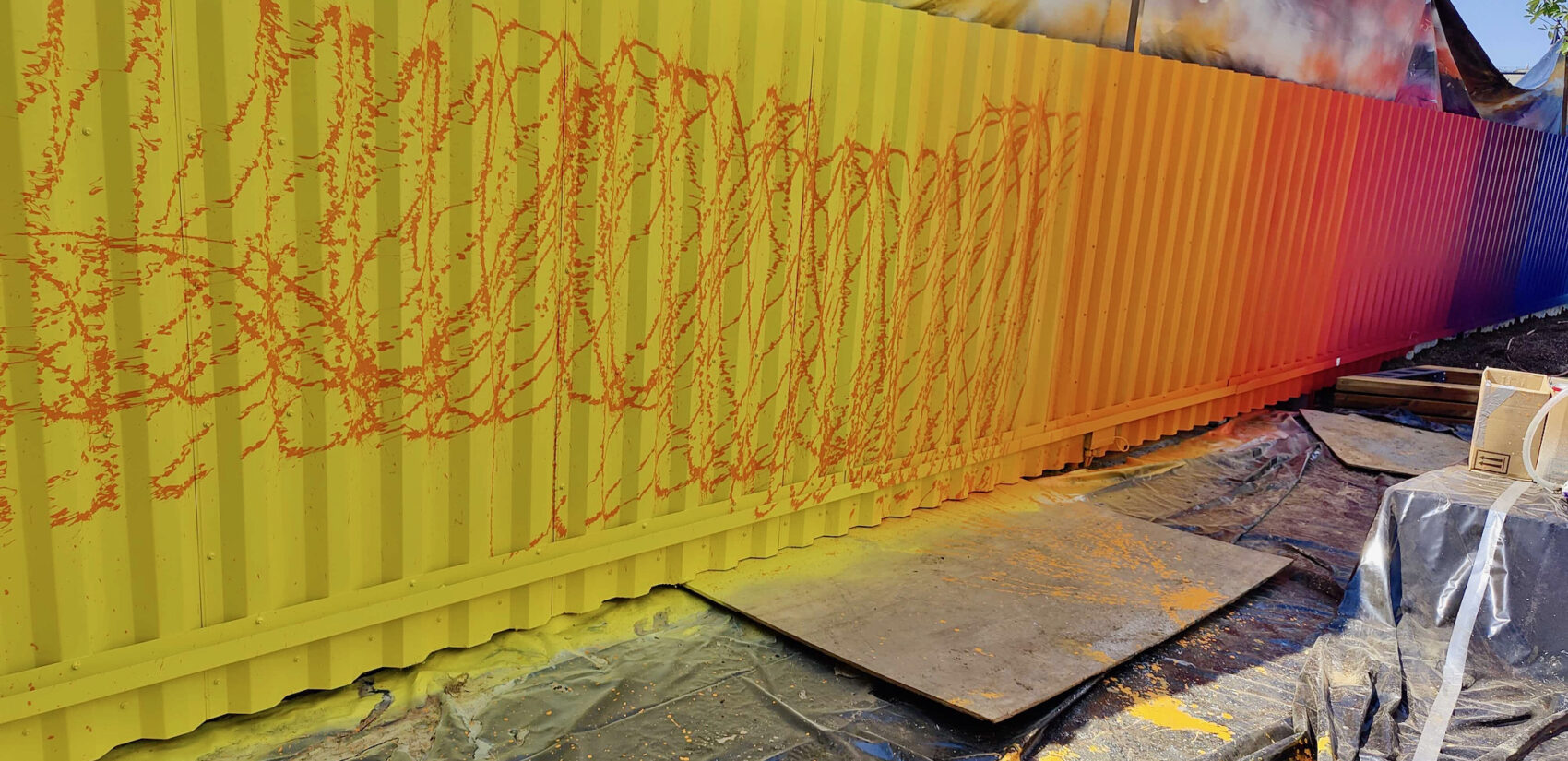 Artist Douglas Hoekzema, aka HOXXOH, created a rainbow-colored underlayer of color, on top of which he sprayed lines of complementary colors through garden hose attachments. (Peter Crimmins/WHYY)
