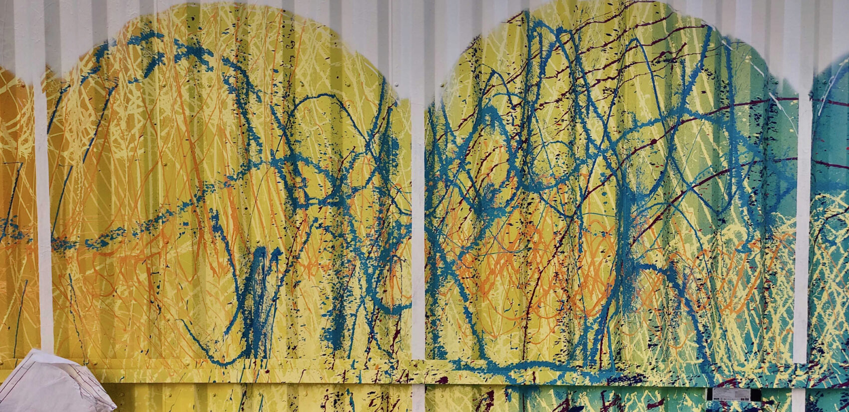 The corrugated steel fence in the garden plaza of The Noble apartment building was painted by Doug Hoekzema, also known as HOXXOH, using his signature style created by spraying paint out of garden sprinklers. (Peter Crimmins/WHYY)