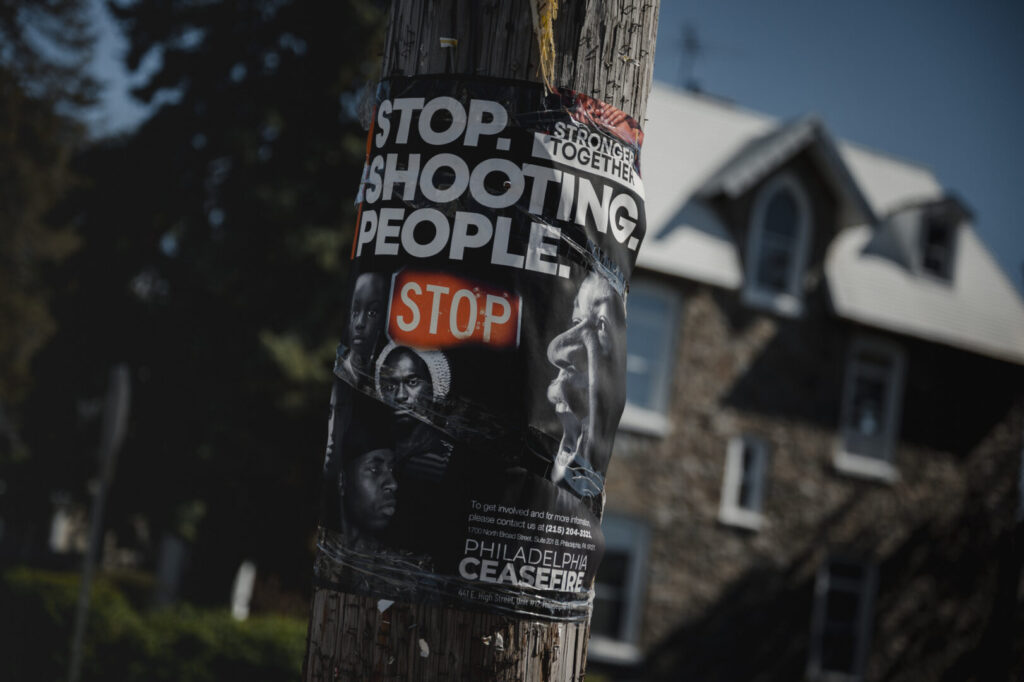 A “Stop. Shooting. People.” Poster by Philadelphia Ceasefire is posted in East Germantown in Philadelphia, PA.
(Hannah Yoon for NPR)