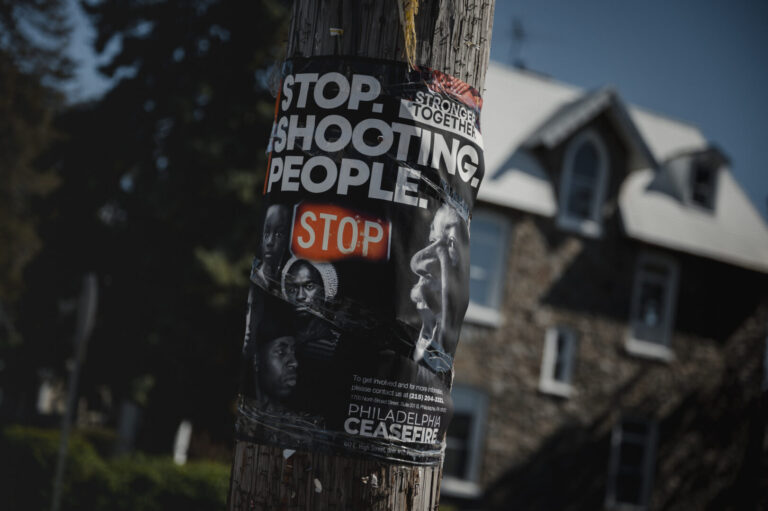 A “Stop. Shooting. People.” Poster by Philadelphia Ceasefire is posted in East Germantown in Philadelphia, PA.
(Hannah Yoon for NPR)