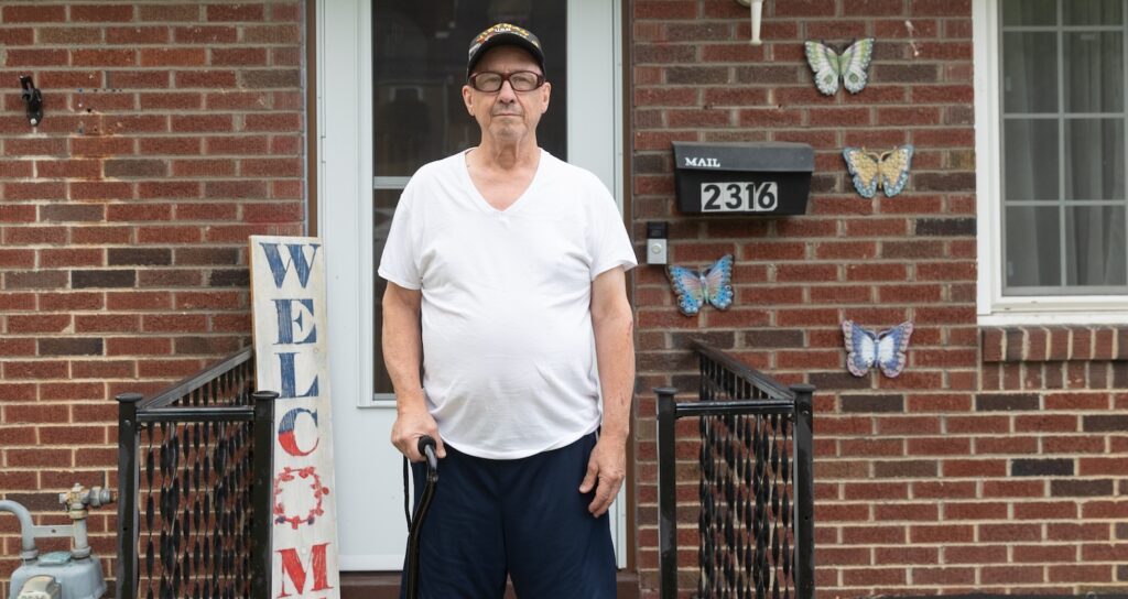 Gary Turney posing in front of his home