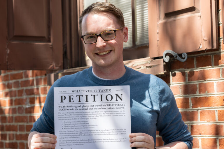 Andrew Wade, M.D., holds the petition that union members and residents at Penn Medicine signed demanding their employer meet their wage proposals after a year of contract negotiations. (Kimberly Paynter/WHYY)