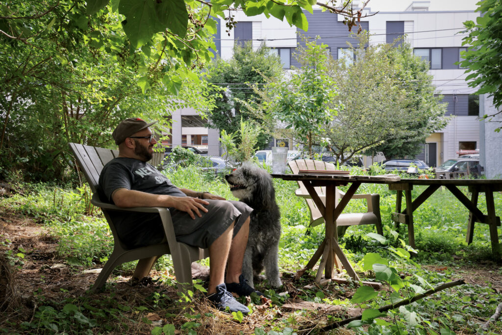 2024 07 31-e lee-jordan baumgarten walter-philadelphia kensington-vacant lot Jordan Baumgarten sits in a chair with his dog