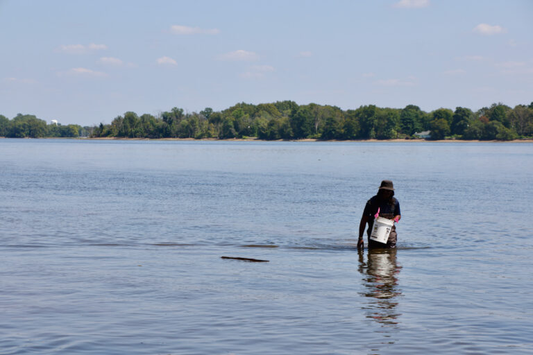 Nathan McWilliams holds a bucket standing in the water